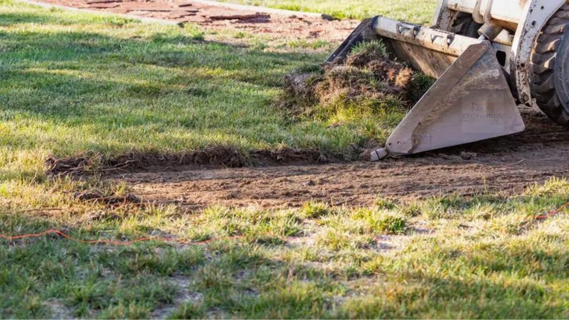 A bulldozer is digging a hole in the ground in a yard.