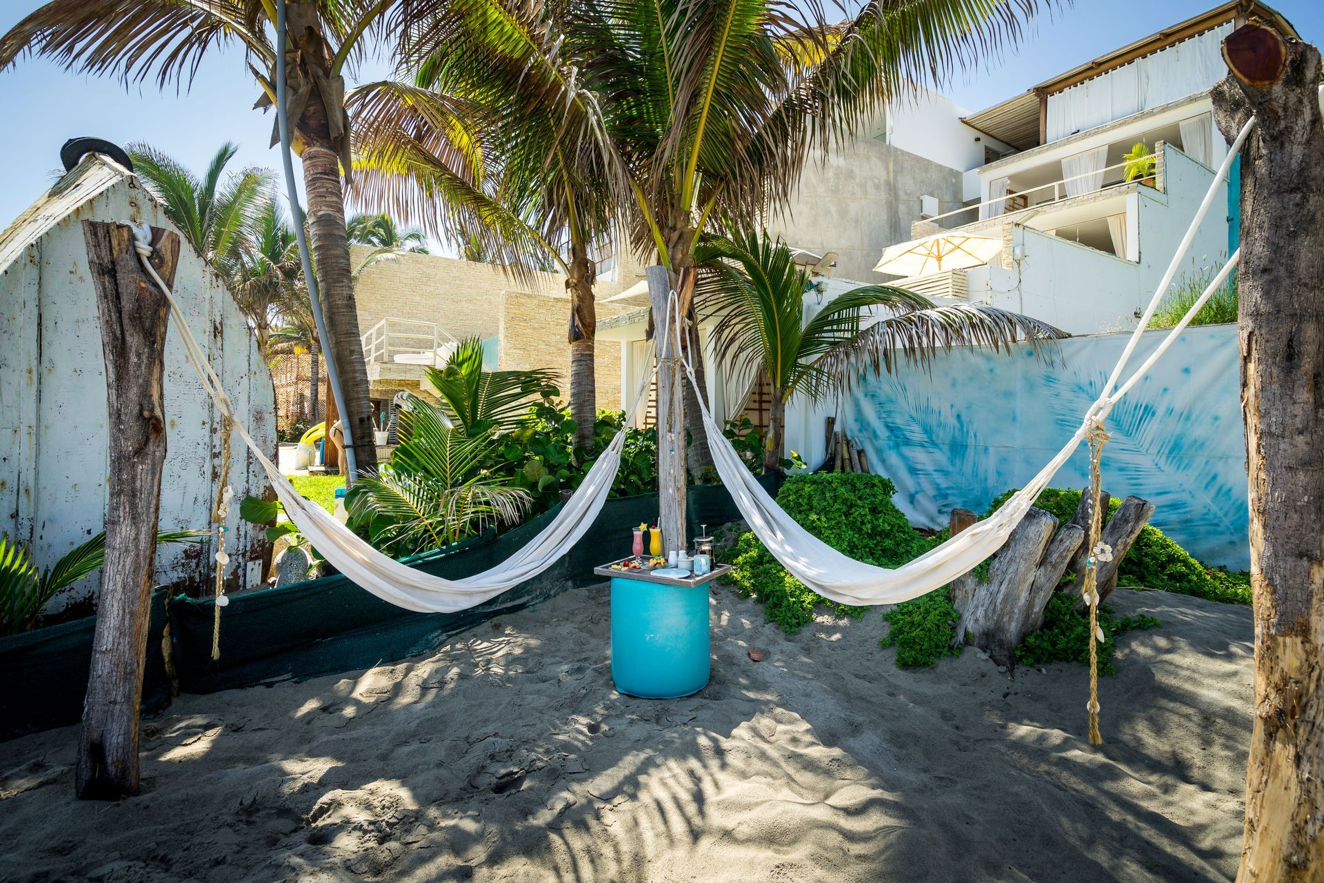 A bunch of hammocks are hanging from trees on a beach.