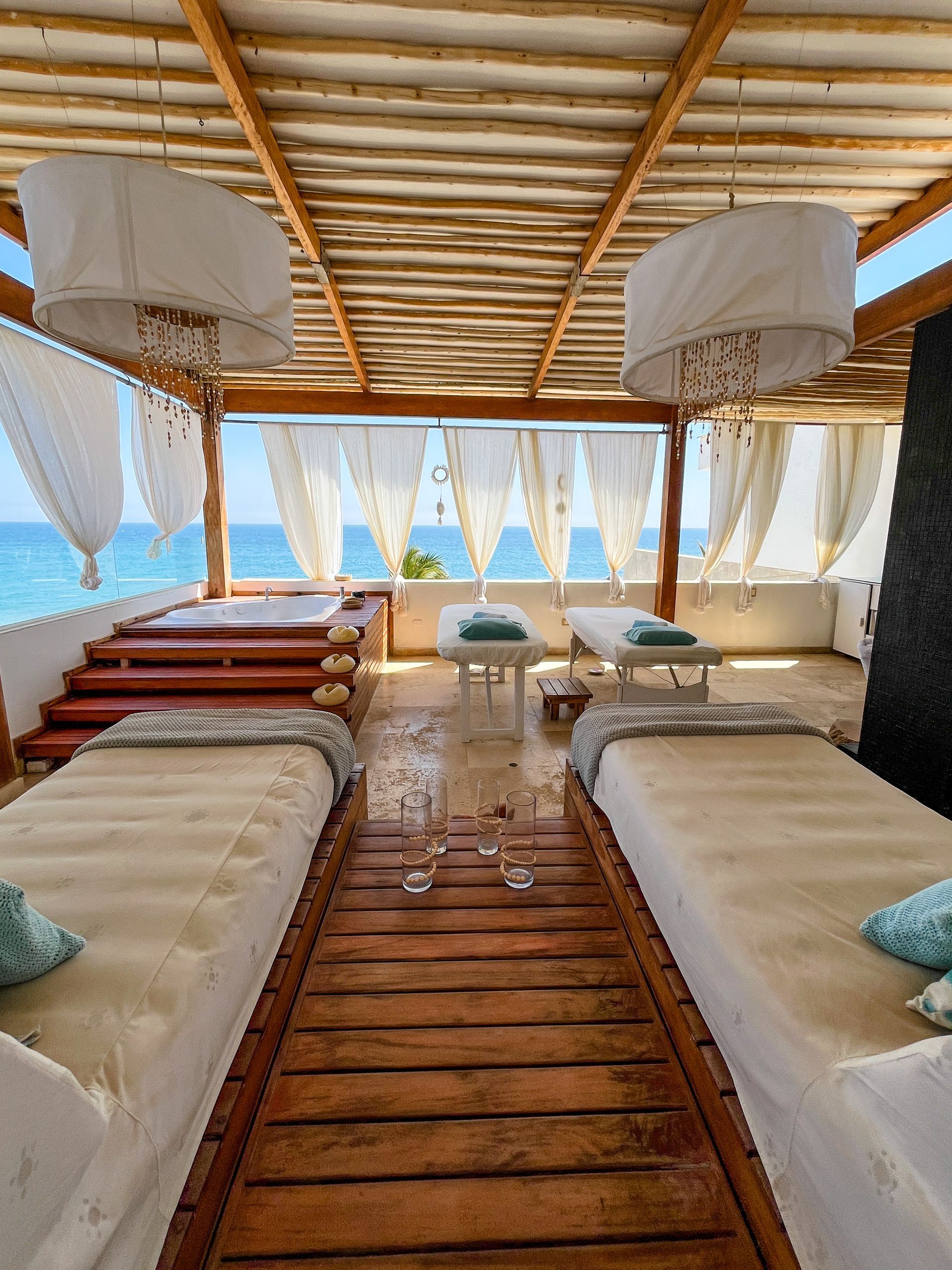 There are two beds in a room with a view of the ocean.