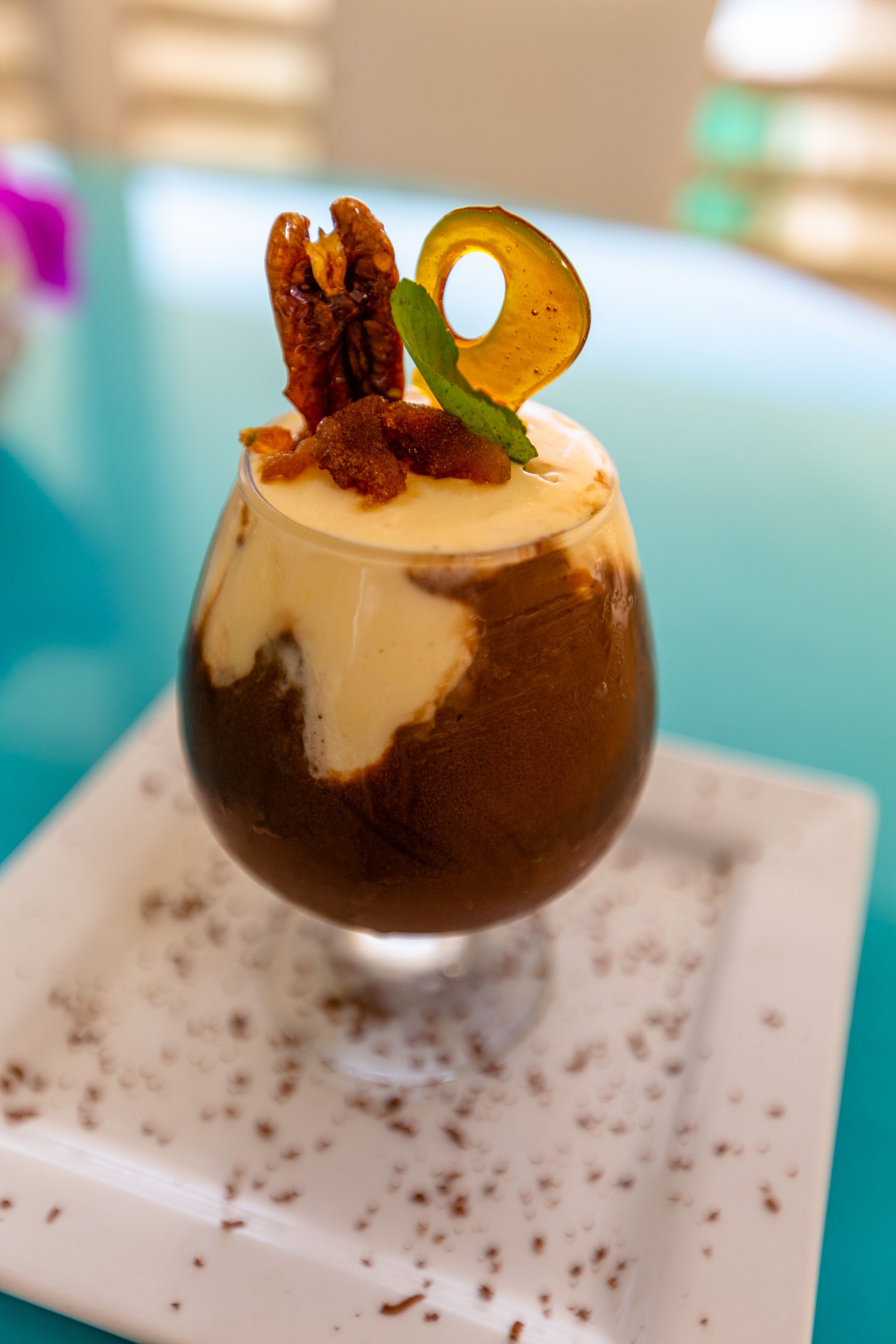 A dessert in a glass on a white plate on a table.