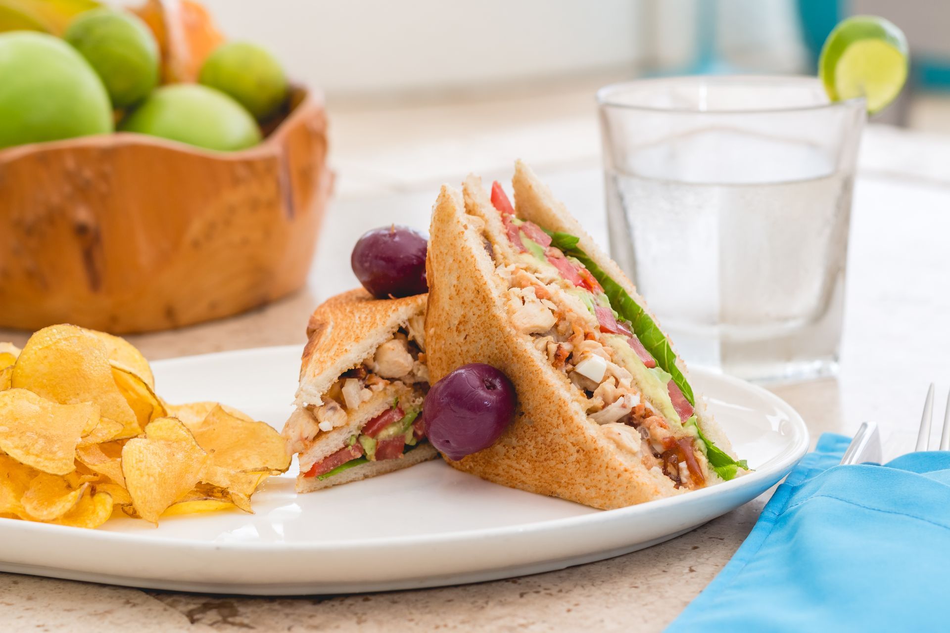 A sandwich and chips on a white plate on a table.