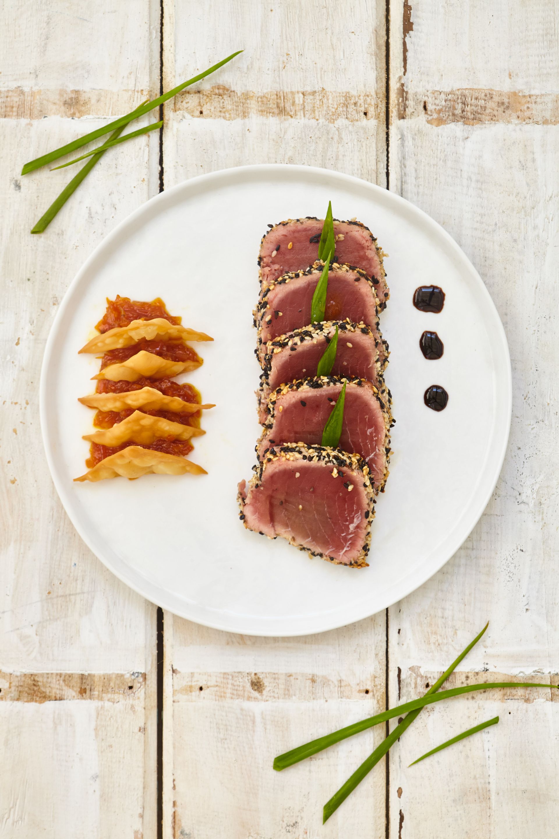 A white plate topped with meat and vegetables on a wooden table