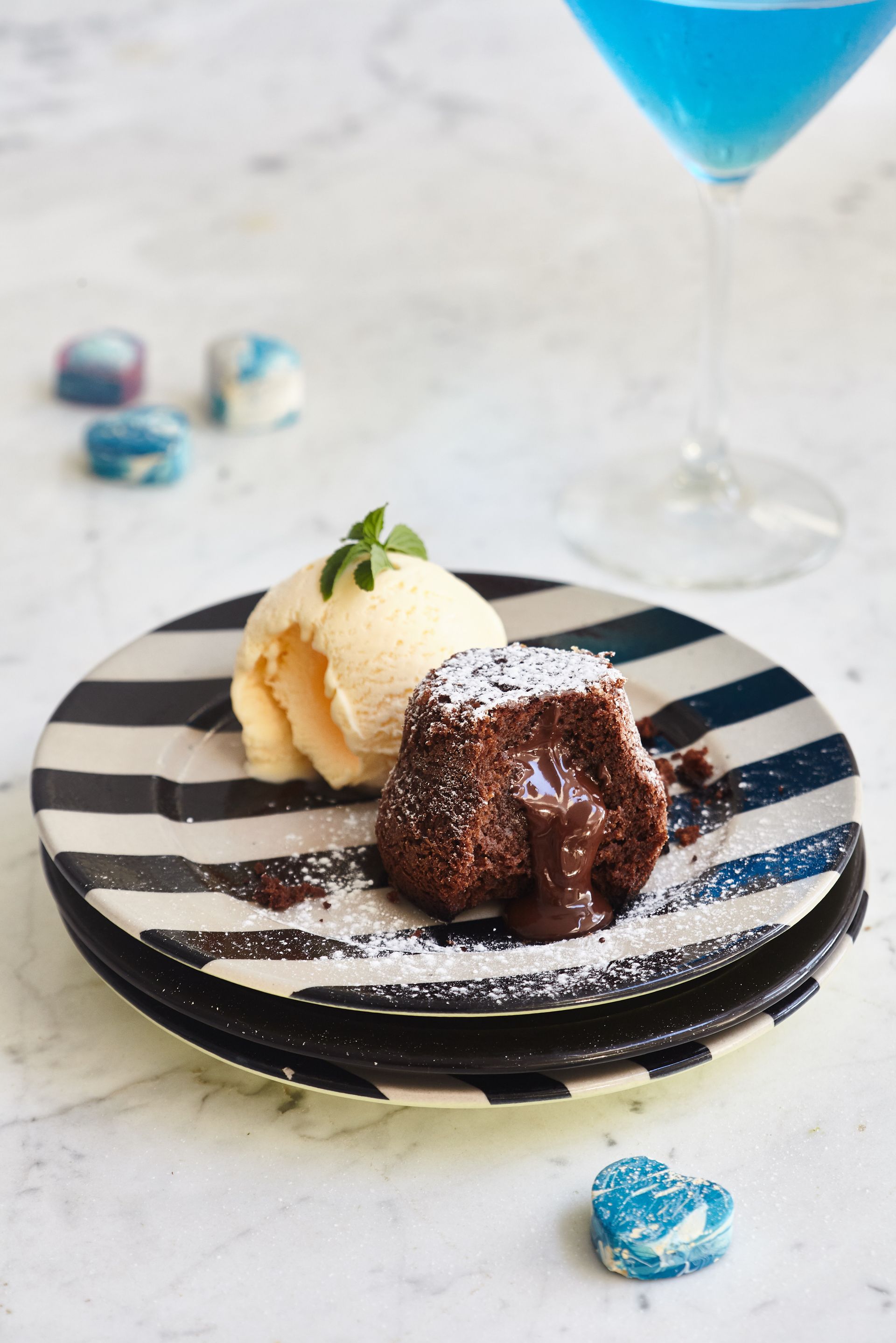 A chocolate lava cake with ice cream on a striped plate