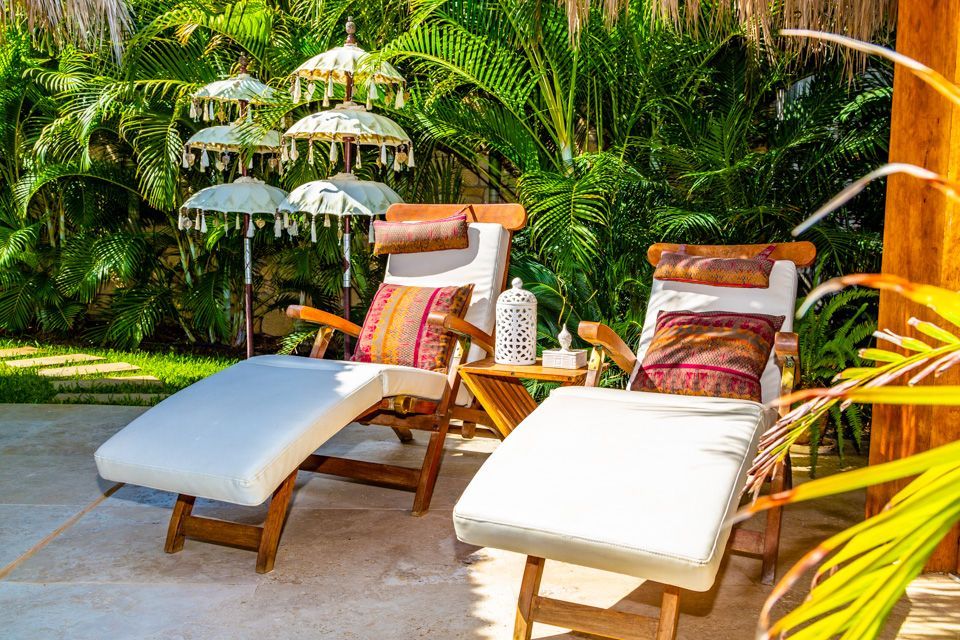 Two lounge chairs are sitting on a patio next to a palm tree.