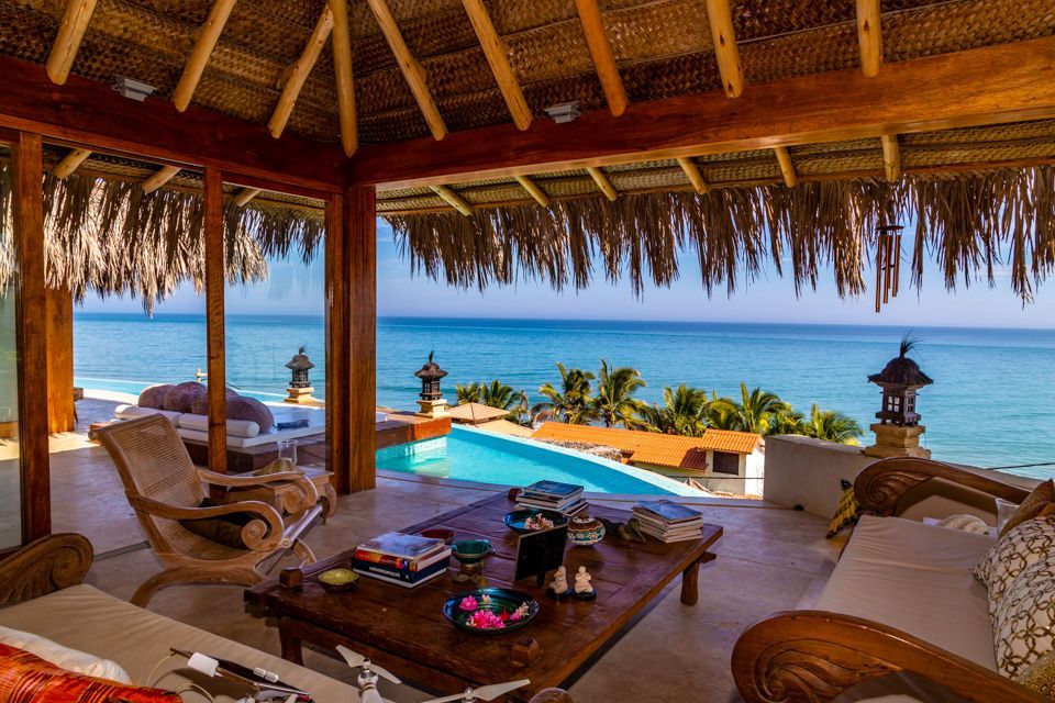 A living room with a view of the ocean and a swimming pool.