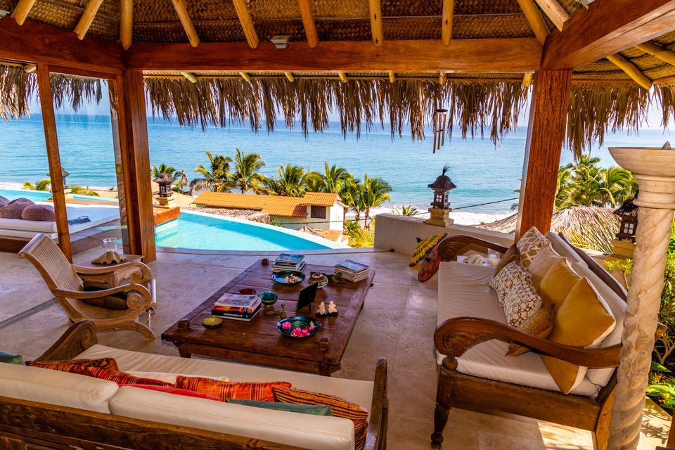 A living room with a couch , table , chairs and a view of the ocean.
