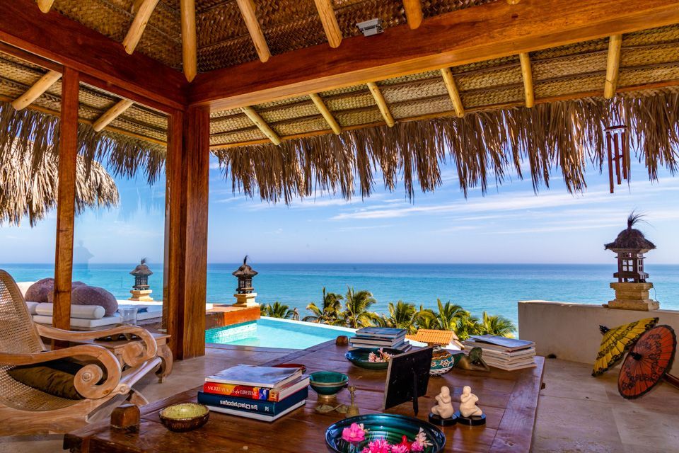 A living room with a table and chairs and a view of the ocean.
