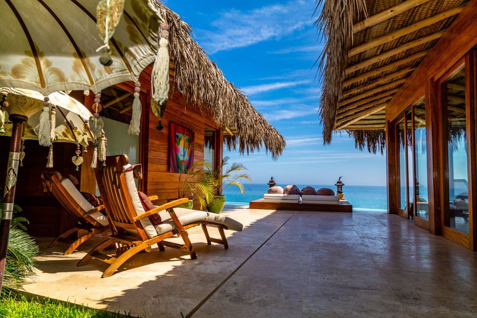 A wooden house with a thatched roof and a view of the ocean