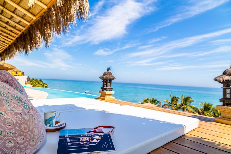 A book is sitting on a bed with a view of the ocean.