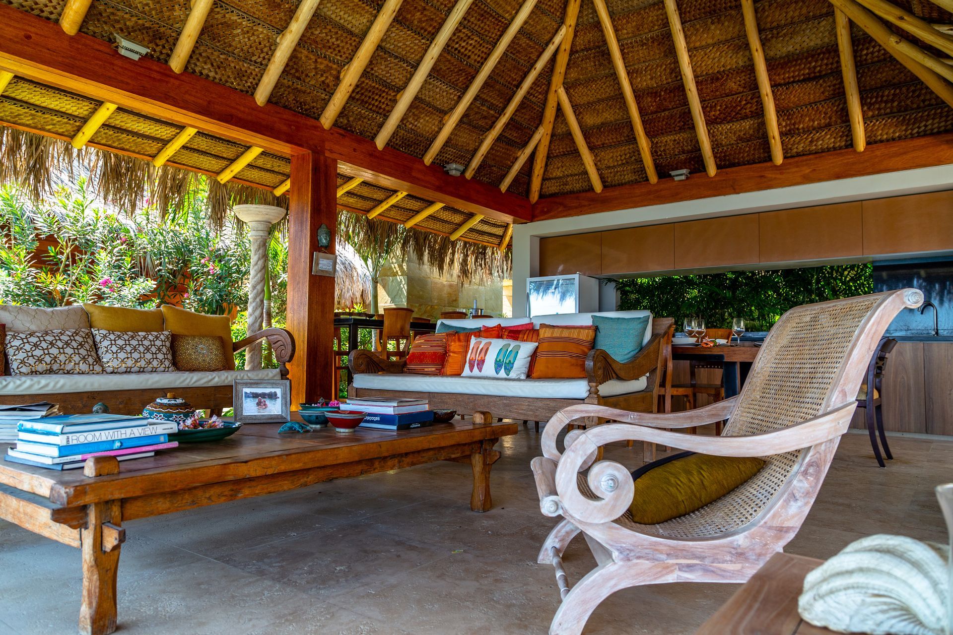 A living room with a table and chairs under a thatched roof.