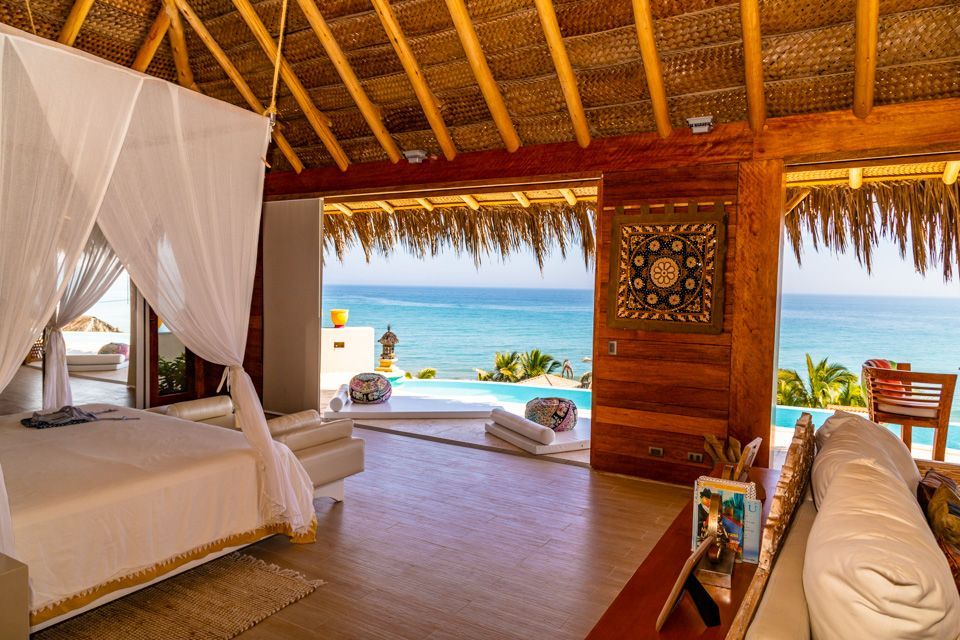 A bedroom with a canopy bed and a view of the ocean