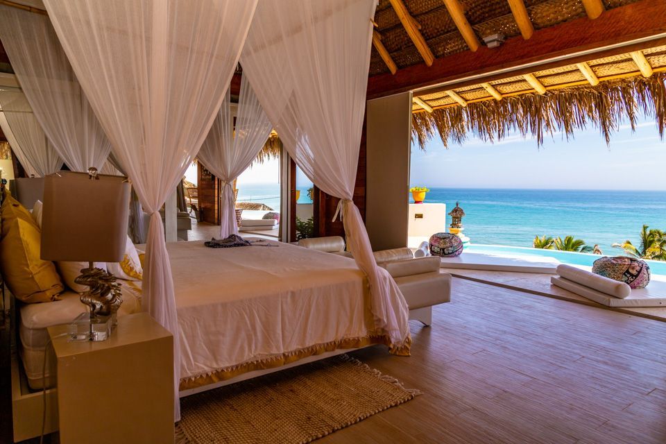 A bedroom with a canopy bed and a view of the ocean.