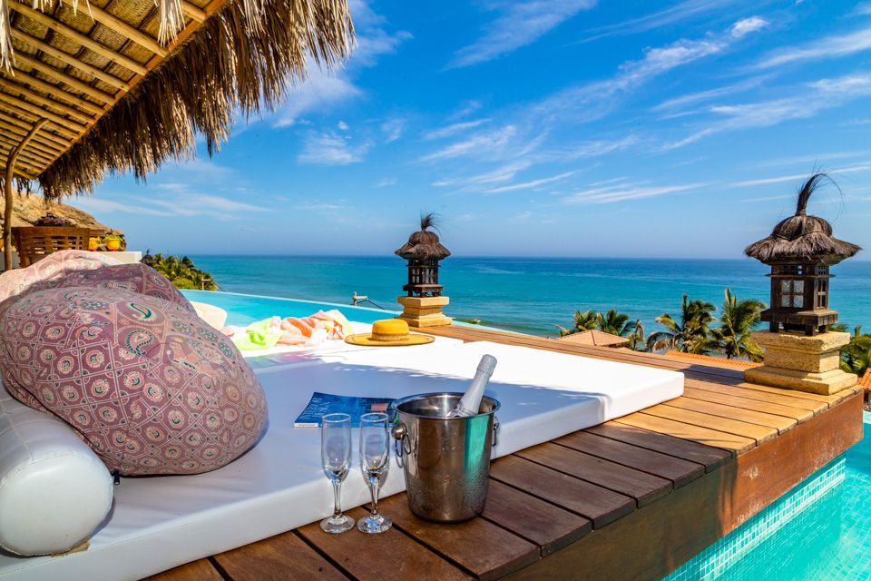 A pool with a view of the ocean and a bucket of champagne.