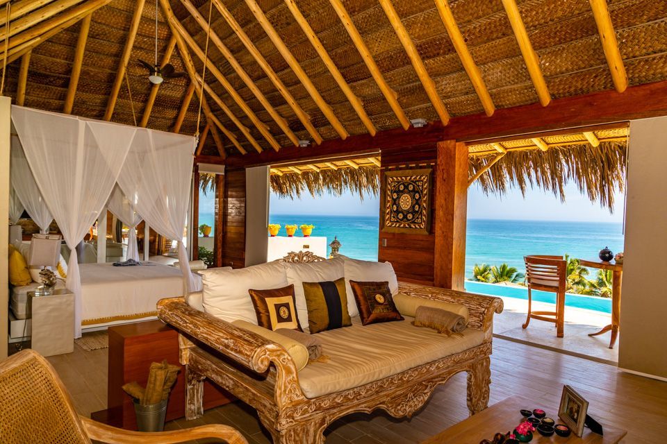 A living room with a couch , chairs , and a view of the ocean.
