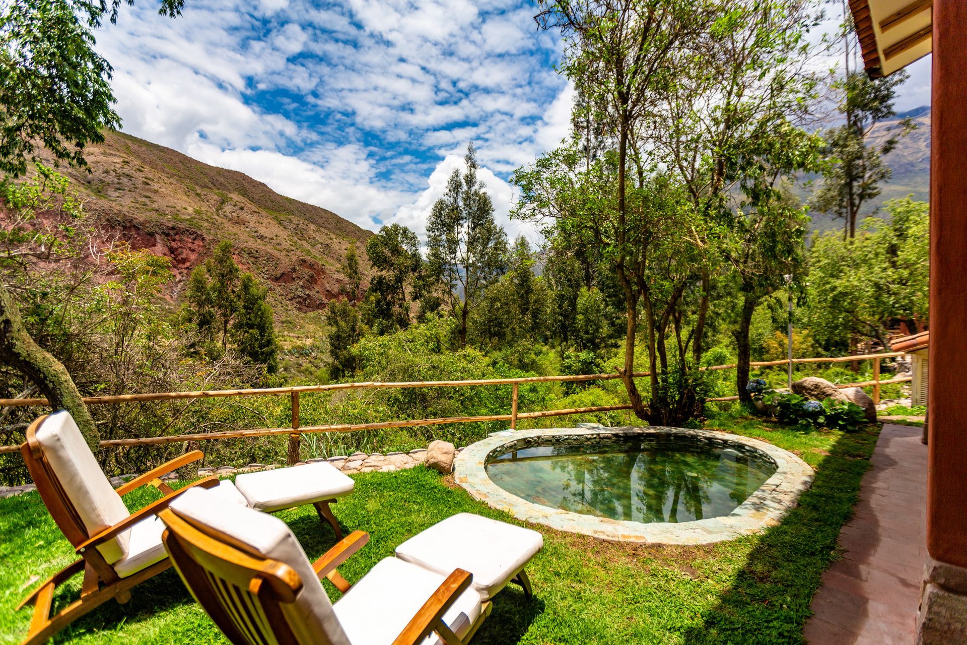 A lawn with chairs and a pool in the middle of it.