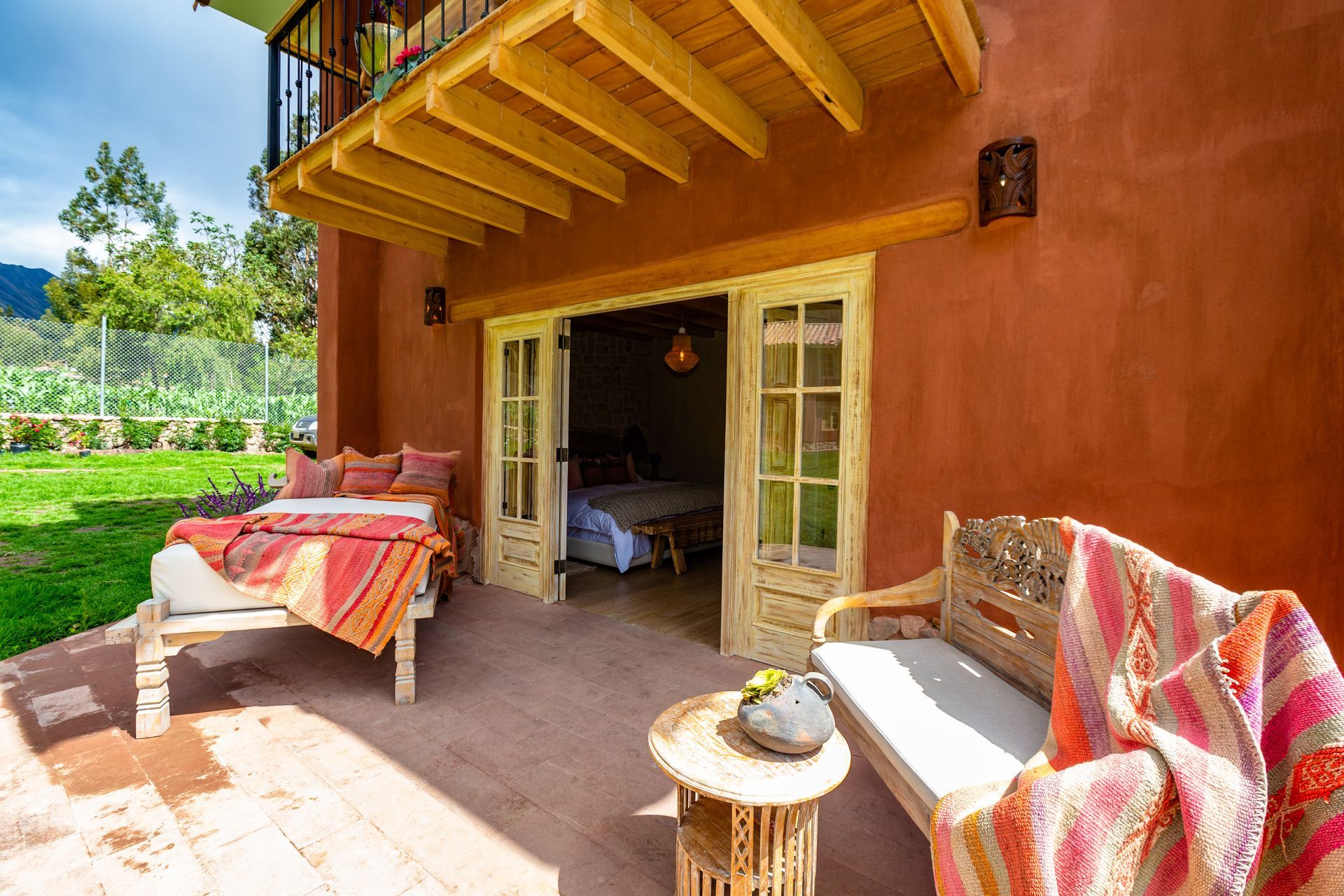 A patio with a bed , couch , table and chairs in front of a house.