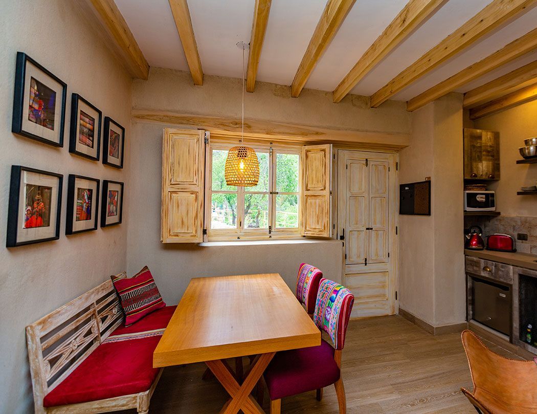 A dining room with a table and chairs in front of a window.
