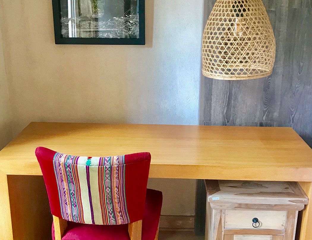 A wooden desk with a chair and a lamp in a room.