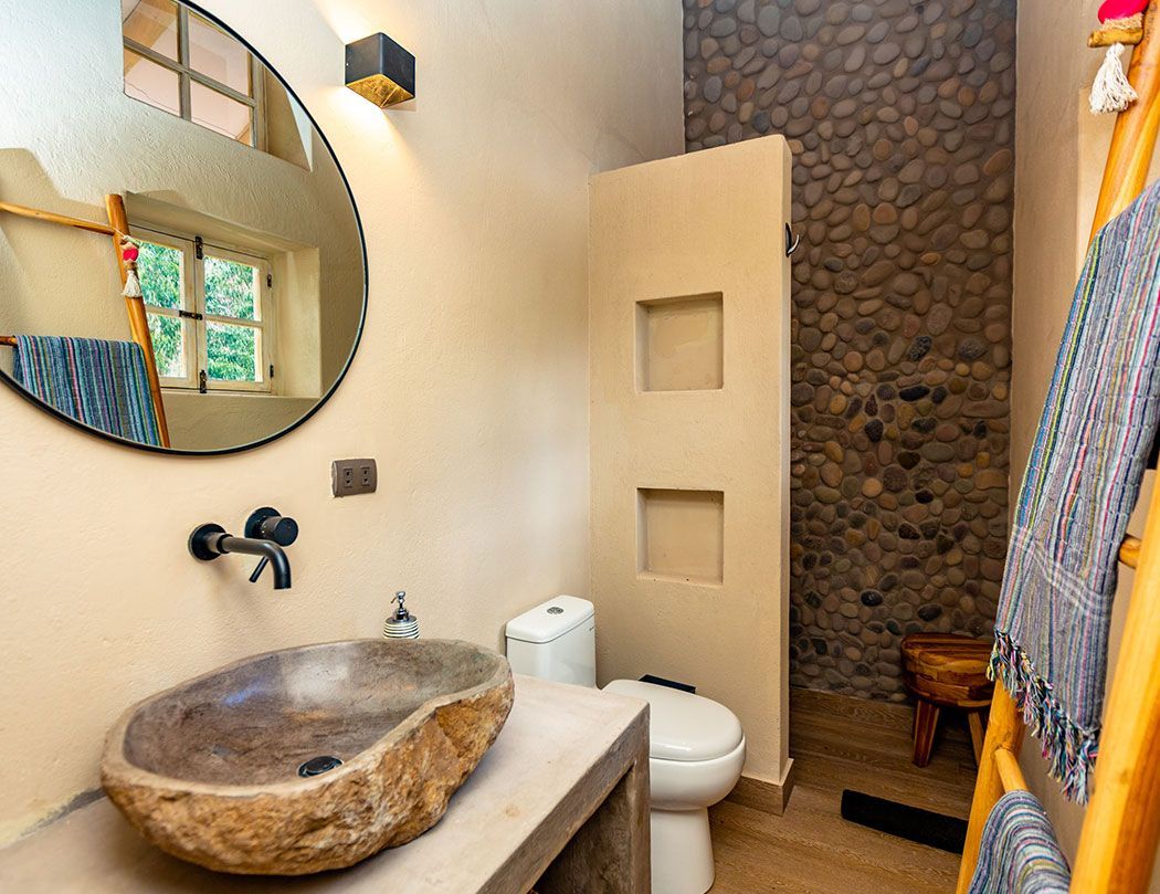 A bathroom with a toilet , sink and mirror.