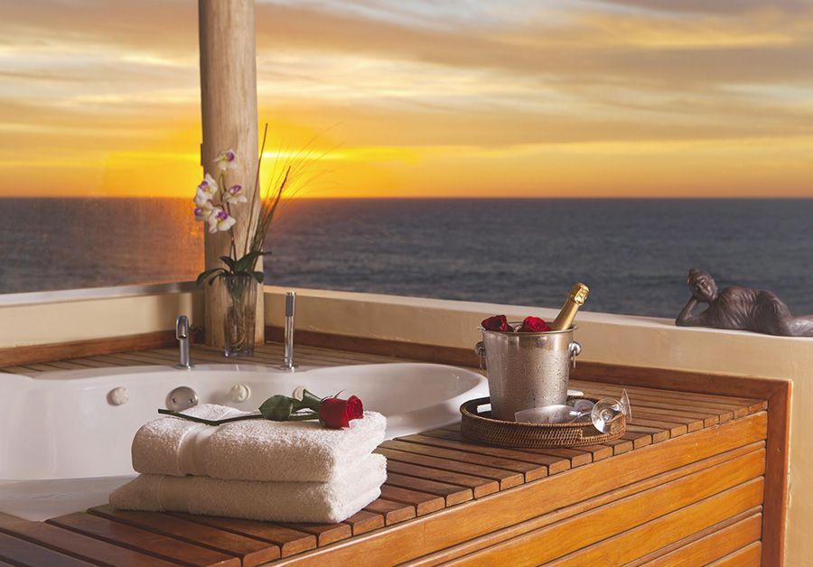 A bathtub with a bucket of champagne and roses on the counter