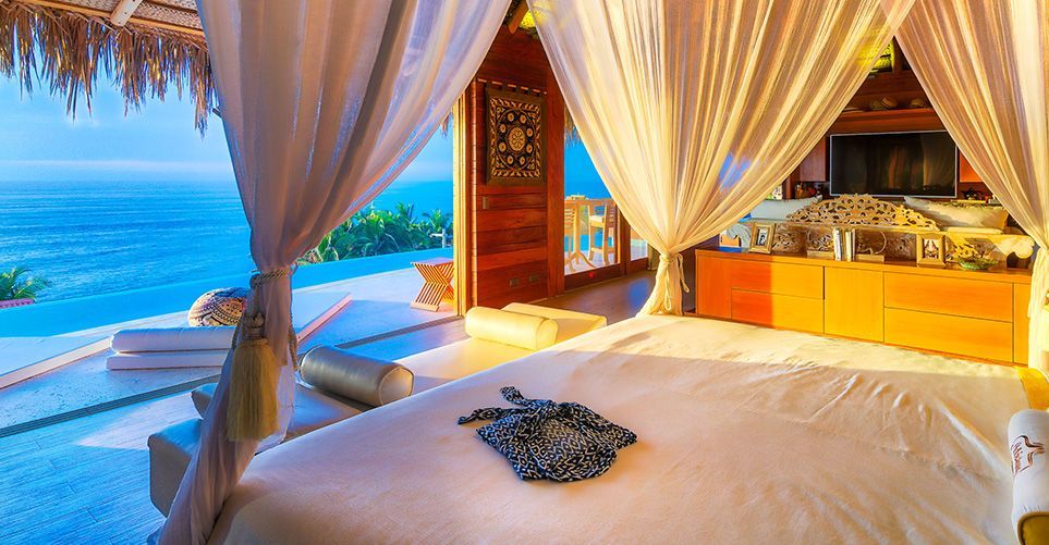 A bedroom with a canopy bed and a view of the ocean.