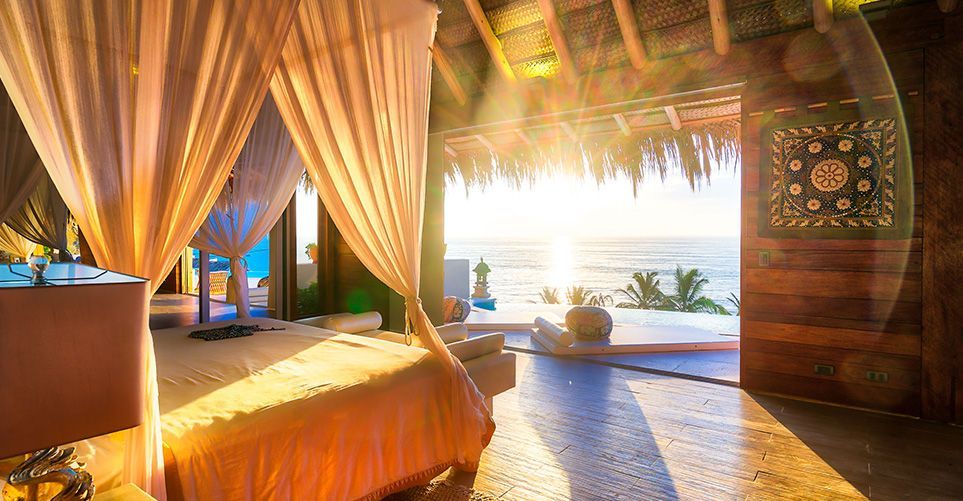A bedroom with a canopy bed and a view of the ocean.