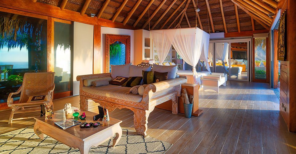 A living room with a couch , table , chairs and a canopy bed.