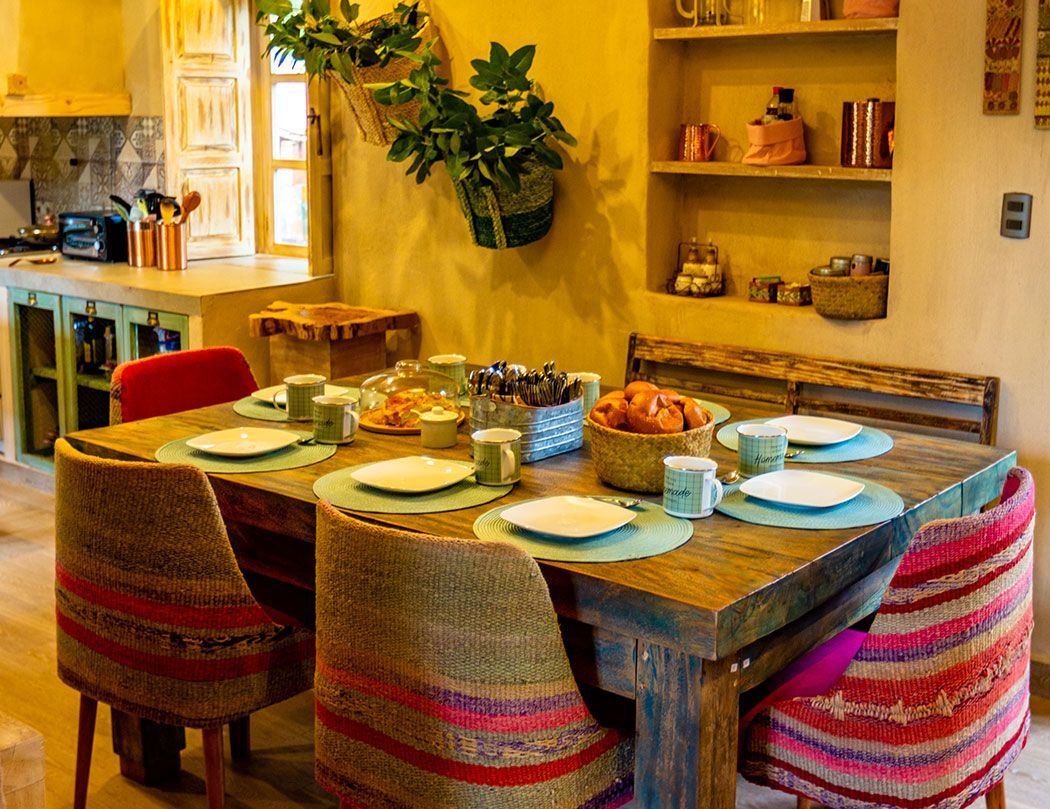 A dining room with a table and chairs and plates on it.