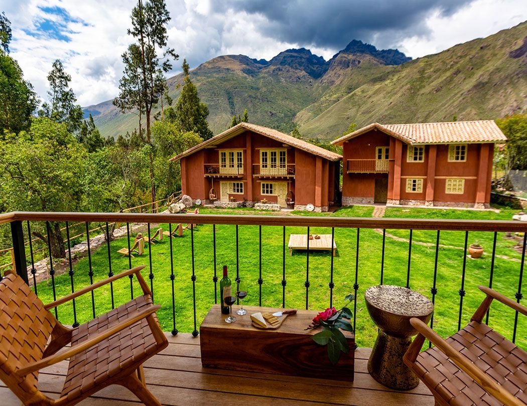 A balcony with two chairs and a table with a bottle of wine on it.