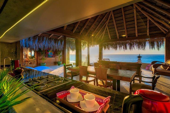 A kitchen with a table and chairs and a view of the ocean.