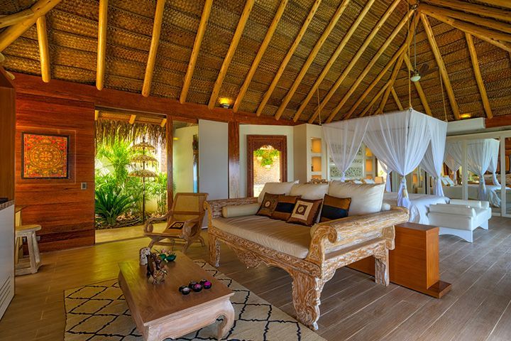 A living room with a couch , table , chairs and a thatched roof.