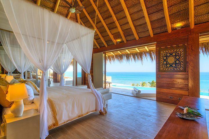 A bedroom with a canopy bed and a view of the ocean.