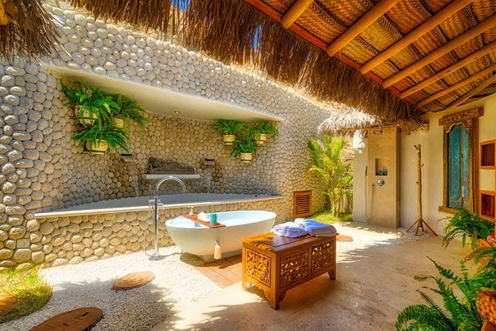 A bathroom with a bathtub and a thatched roof.