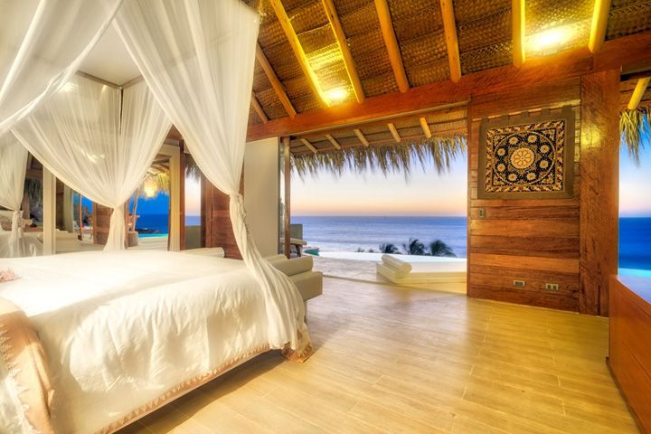 A bedroom with a canopy bed and a view of the ocean.