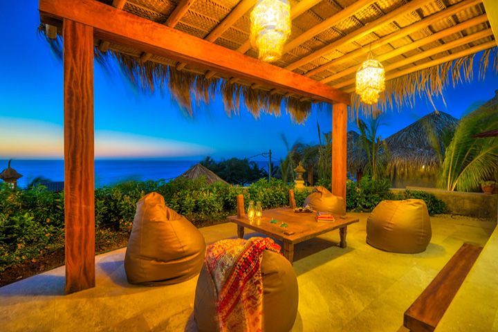 A patio with bean bag chairs and a table with a view of the ocean.