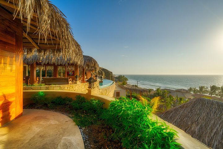 A house with a thatched roof overlooking the ocean.