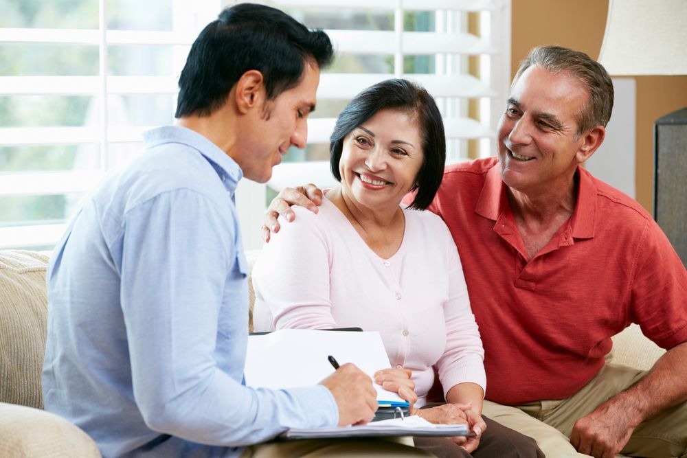 Man Talking With a Smiling Couple on a Couch — Midcoast Financial Planning Group in Taree, NSW