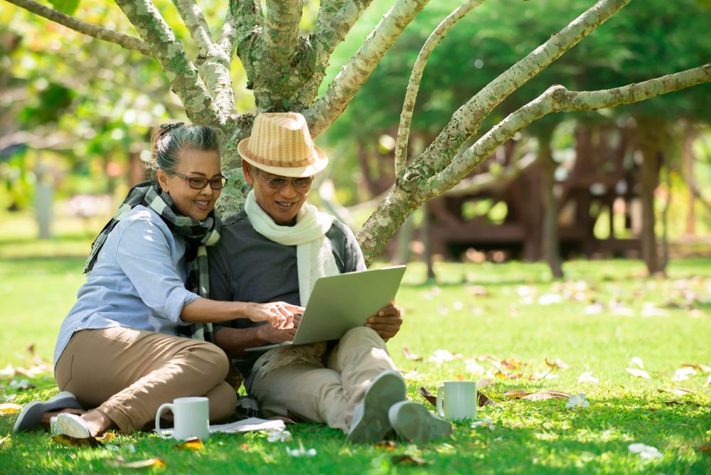 Couple Sitting on Grass Under a Tree — Midcoast Financial Planning Group in Taree, NSW