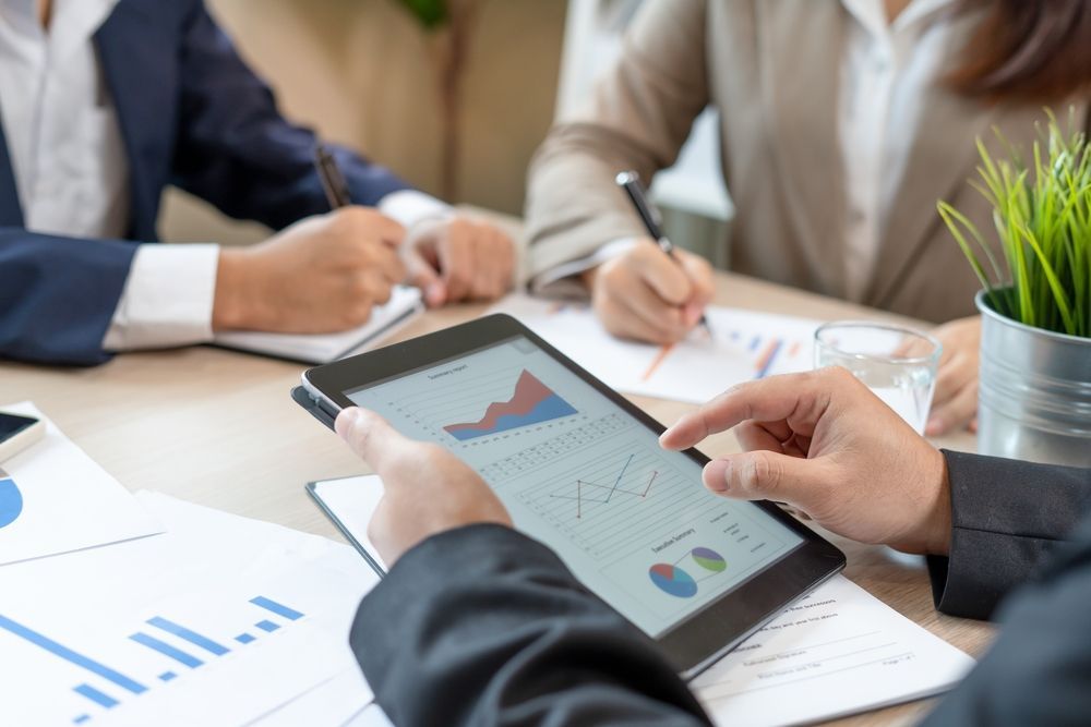 Business Colleagues Analyze Charts on a Tablet at a Table — Midcoast Financial Planning Group in Tuncurry, NSW