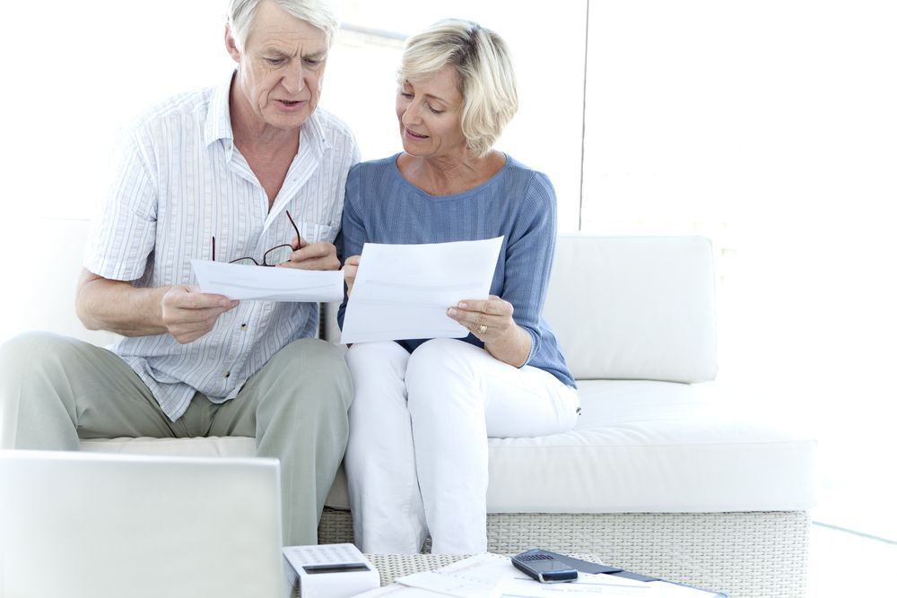 Older Couple Reviewing Documents Together on a White Couch — Midcoast Financial Planning Group in Taree, NSW