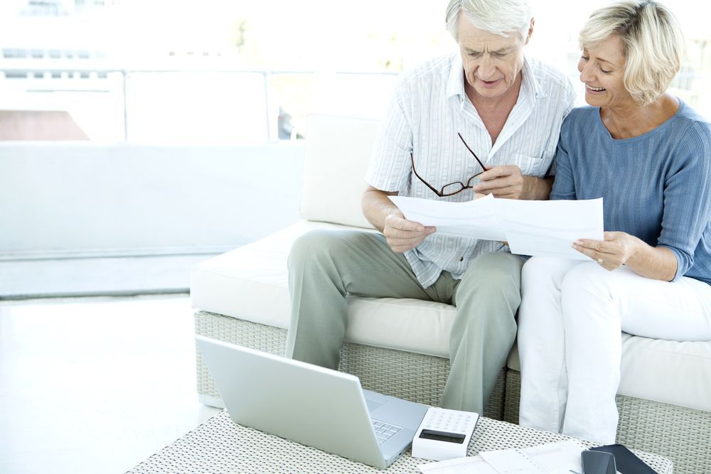 Older Couple Reviewing Documents With a Laptop — Midcoast Financial Planning Group in Forster, NSW
