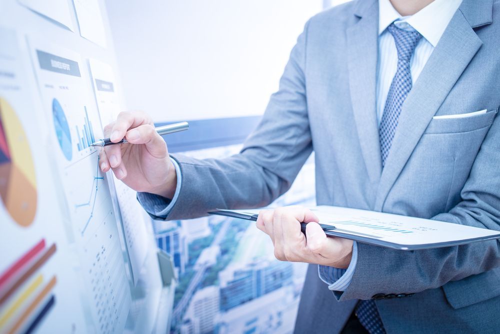 Person in a Gray Suit Analyzing Charts and Graphs on a Whiteboard — Midcoast Financial Planning Group in Tuncurry, NSW