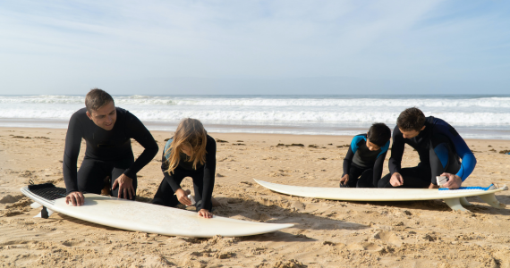 Two Adults And Two Children In Wetsuits — Midcoast Financial Planning Group in Tuncurry, NSW