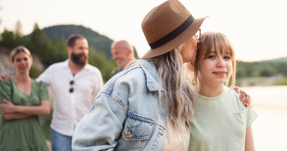 Woman in Hat Kisses Another Woman's Cheek Outdoors — Midcoast Financial Planning Group in Tuncurry, NSW