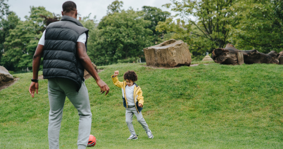Man and Child Playing Soccer in A Park — Midcoast Financial Planning Group in Tuncurry, NSW