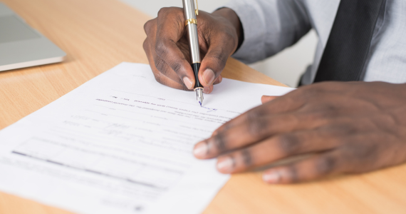 Person's Hands Writing With a Pen— Midcoast Financial Planning Group in Tuncurry, NSW