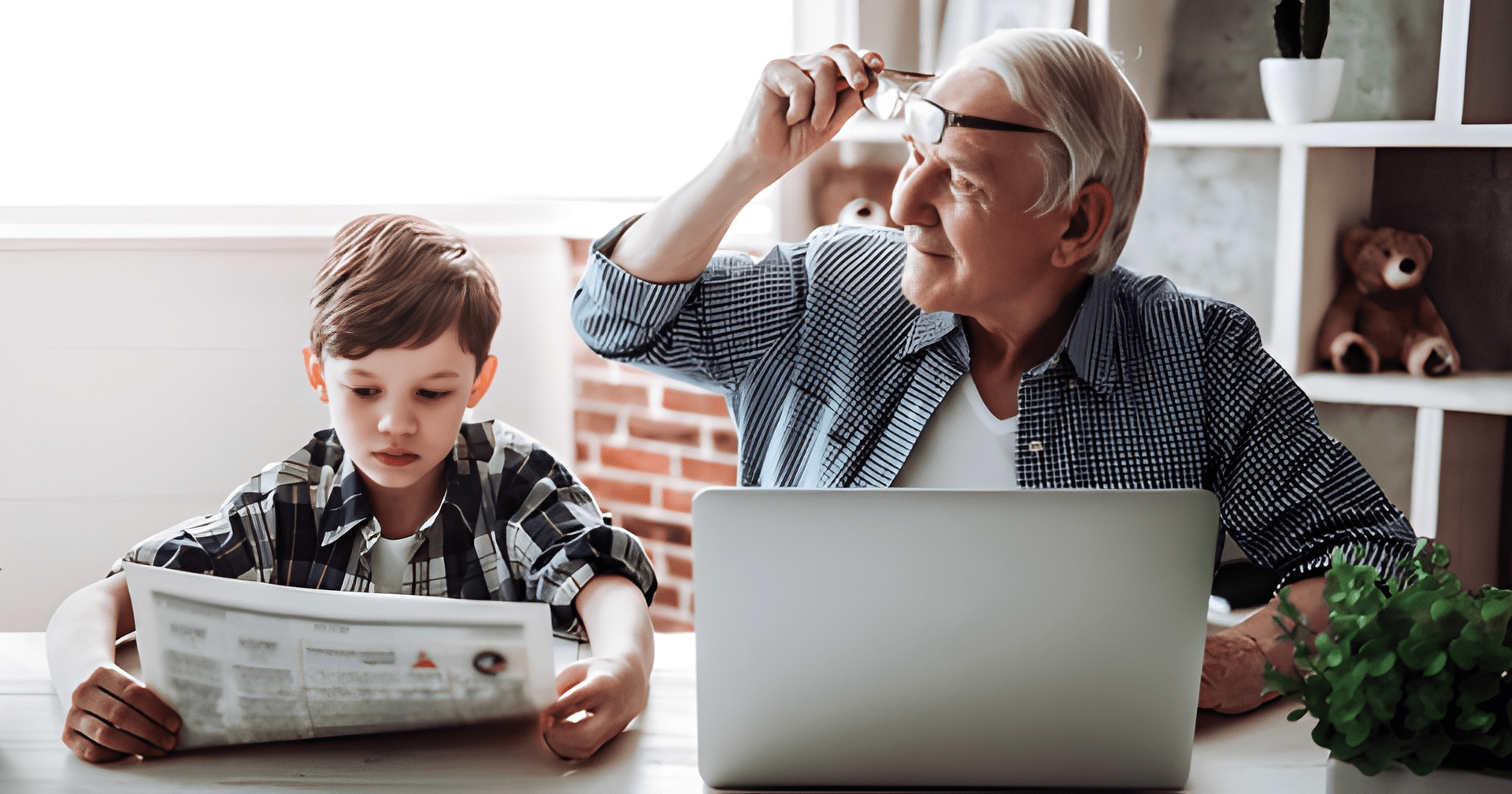 Boy Reading Newspaper, Elderly Man Holding Glasses, Laptop, Indoor Setting — Midcoast Financial Planning Group in Tuncurry, NSW
