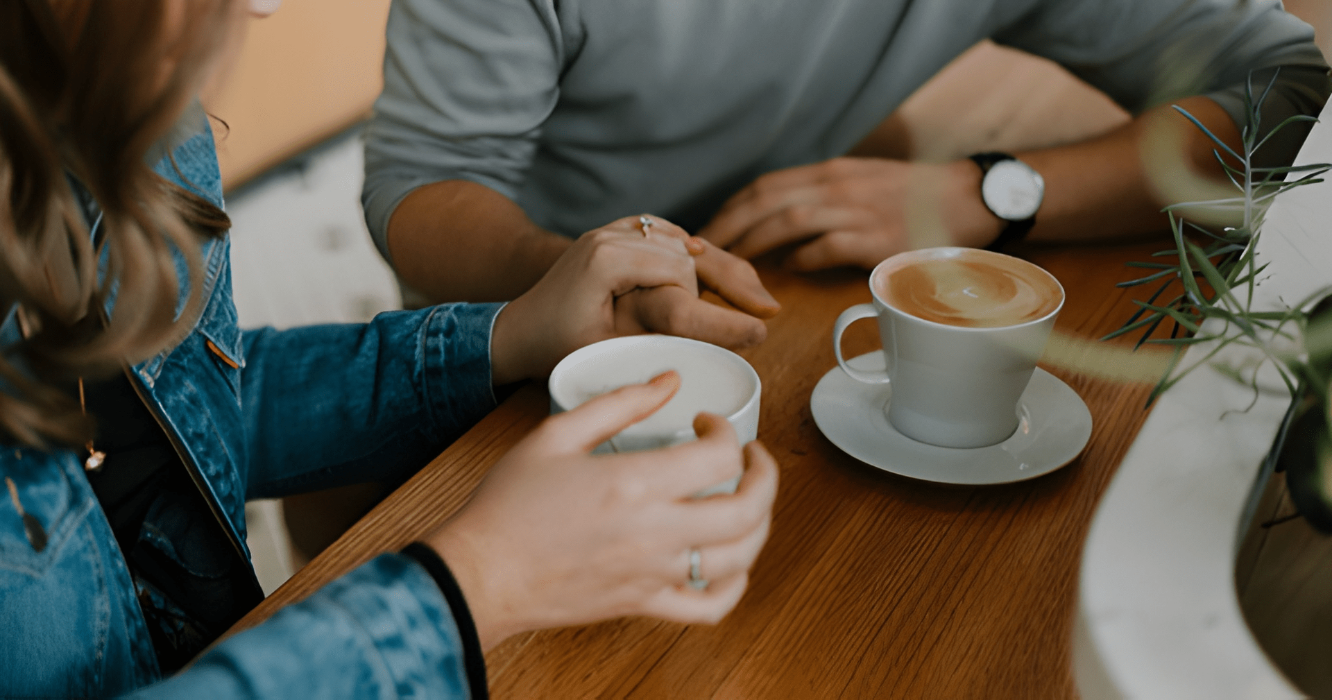 Couple Holding Hands Over a Wooden Table — Midcoast Financial Planning Group in Tuncurry, NSW