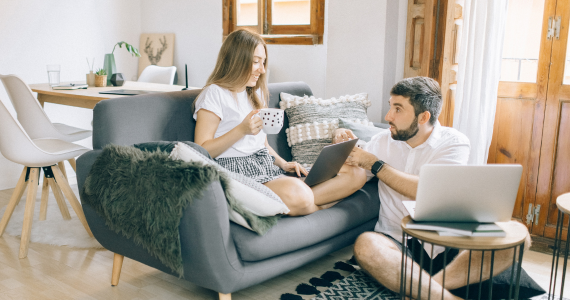 Woman and Man Working on Laptops in A Living Room, Smiling, with Coffee — Midcoast Financial Planning Group in Tuncurry, NSW