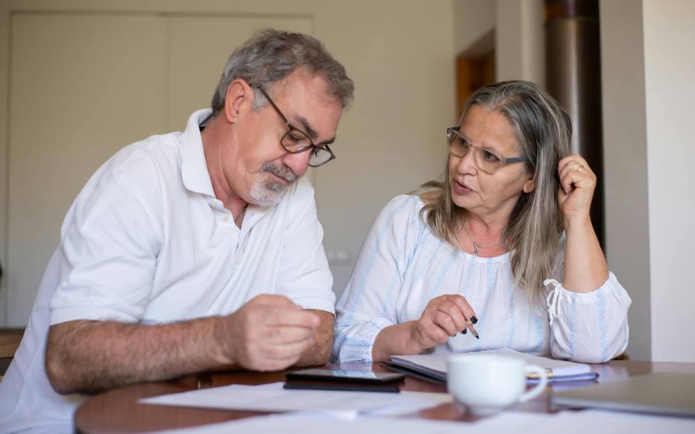 An Older Couple Reviewing Documents at a Table — Midcoast Financial Planning Group in Tuncurry, NSW
